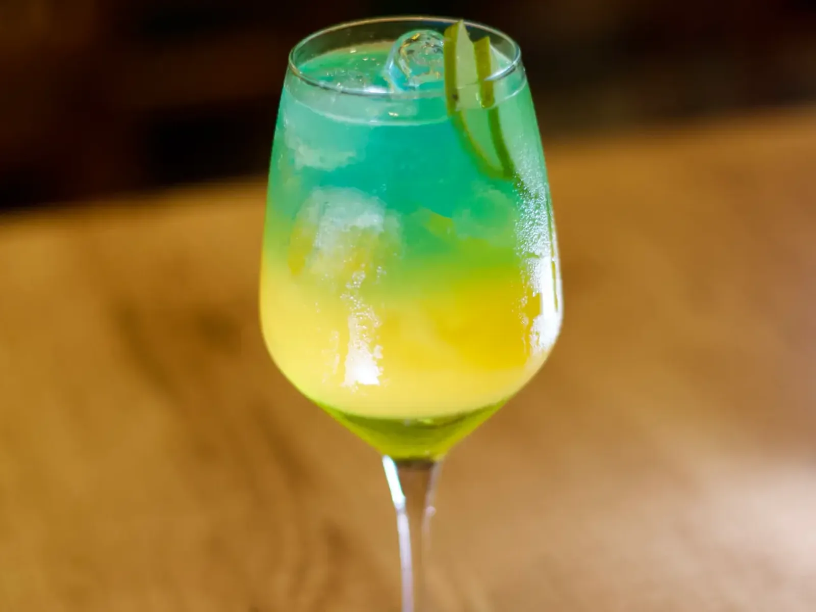 Drink autoral em camadas verde e amarela servido em taça no Nuboa Sushi